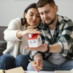 couple-holding-small-house-medium-shot